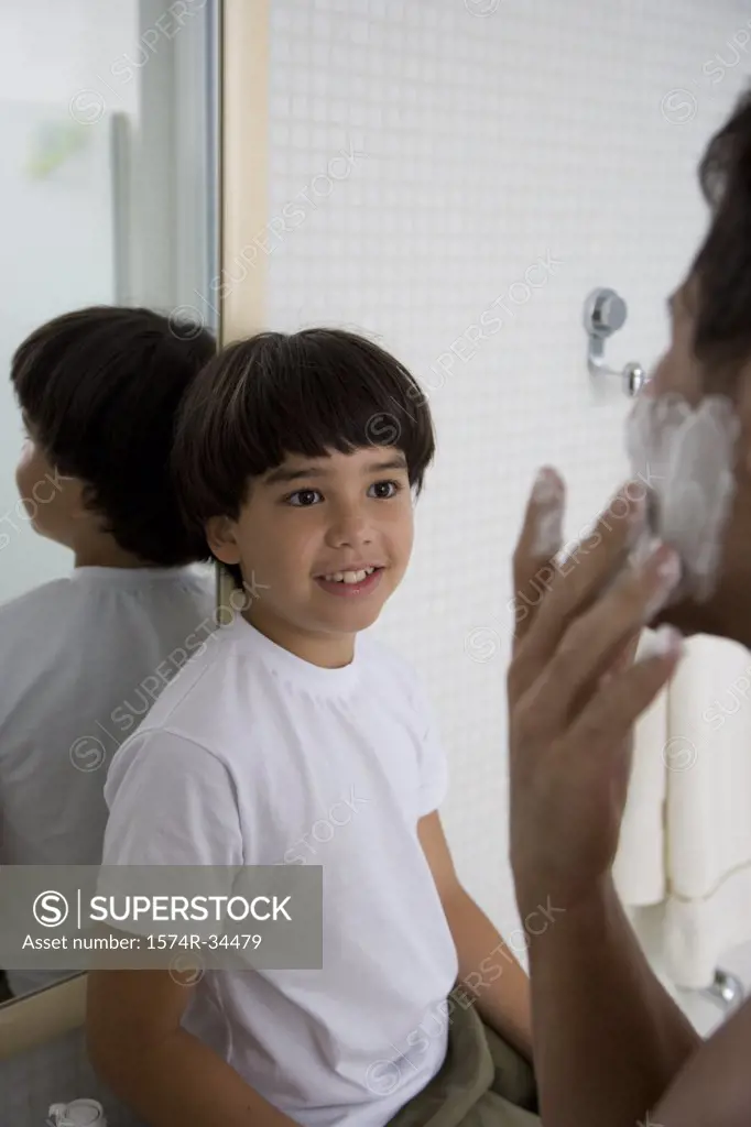 Boy watching his father shave