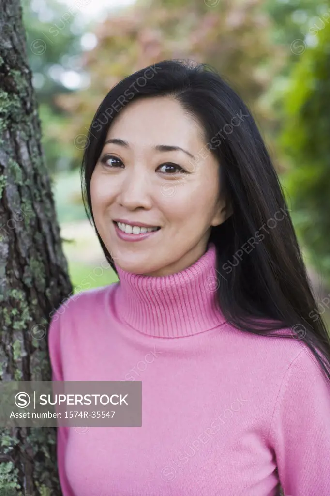 Portrait of woman leaning against tree