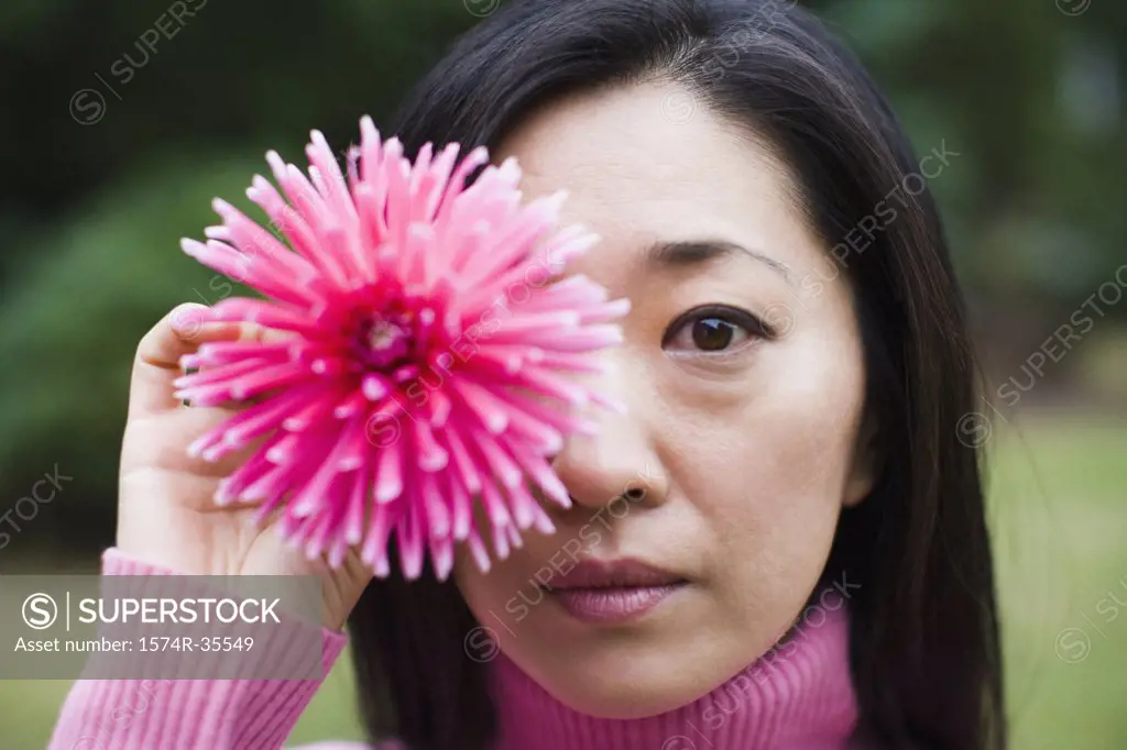 Woman holding flower in front of her eye