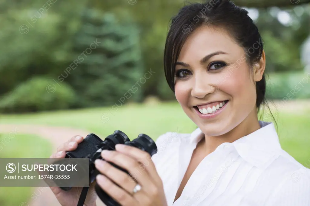 Happy woman holding binoculars and smiling