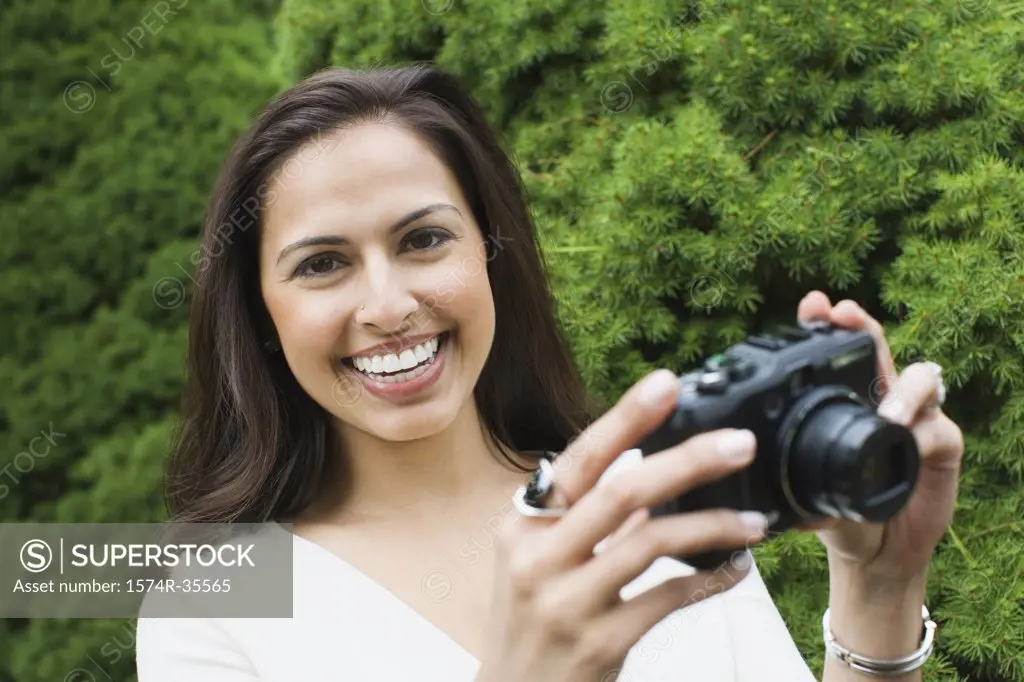 Happy woman holding a camera and smiling