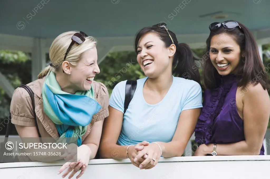 Three women leaning against wall and smiling