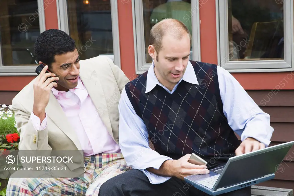 Two businessmen using laptop and mobile phone