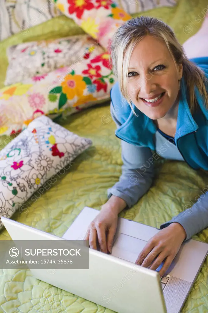 Woman working on laptop in bedroom