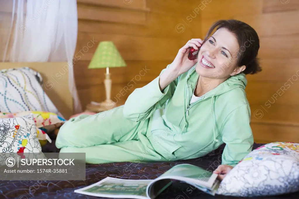 Woman reclining on bed and using mobile phone