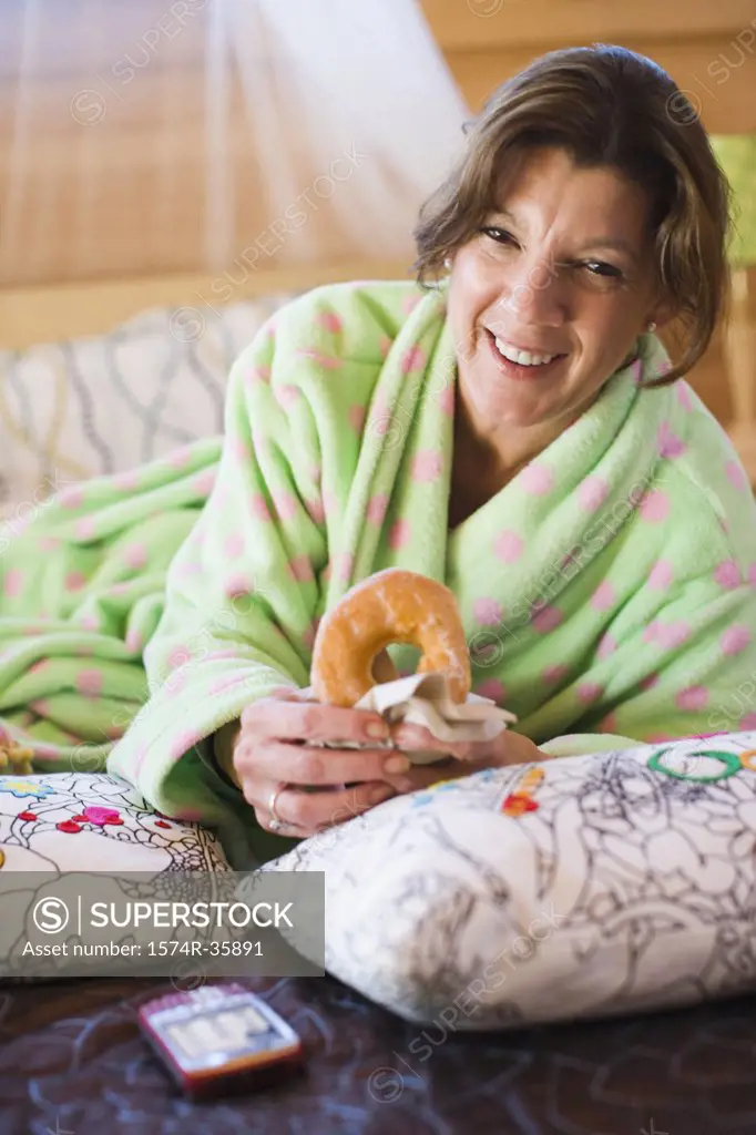 Woman holding a donut on the bed