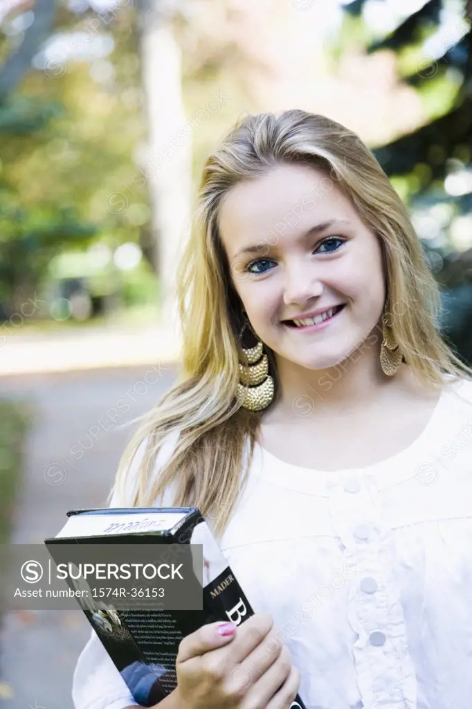 Teenage girl holding a book and smiling