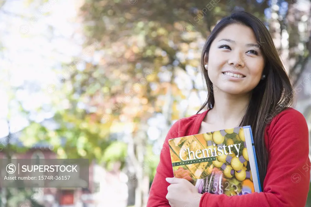 Student holding a book and smiling