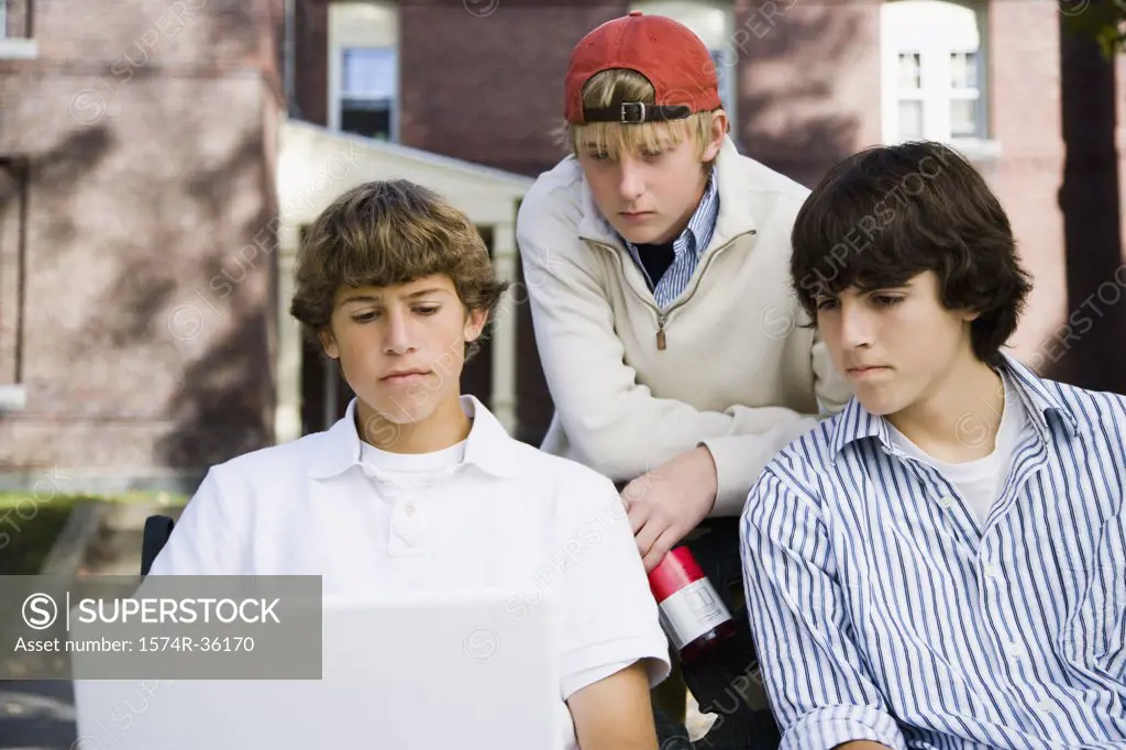 Students working on a laptop with his friends beside him