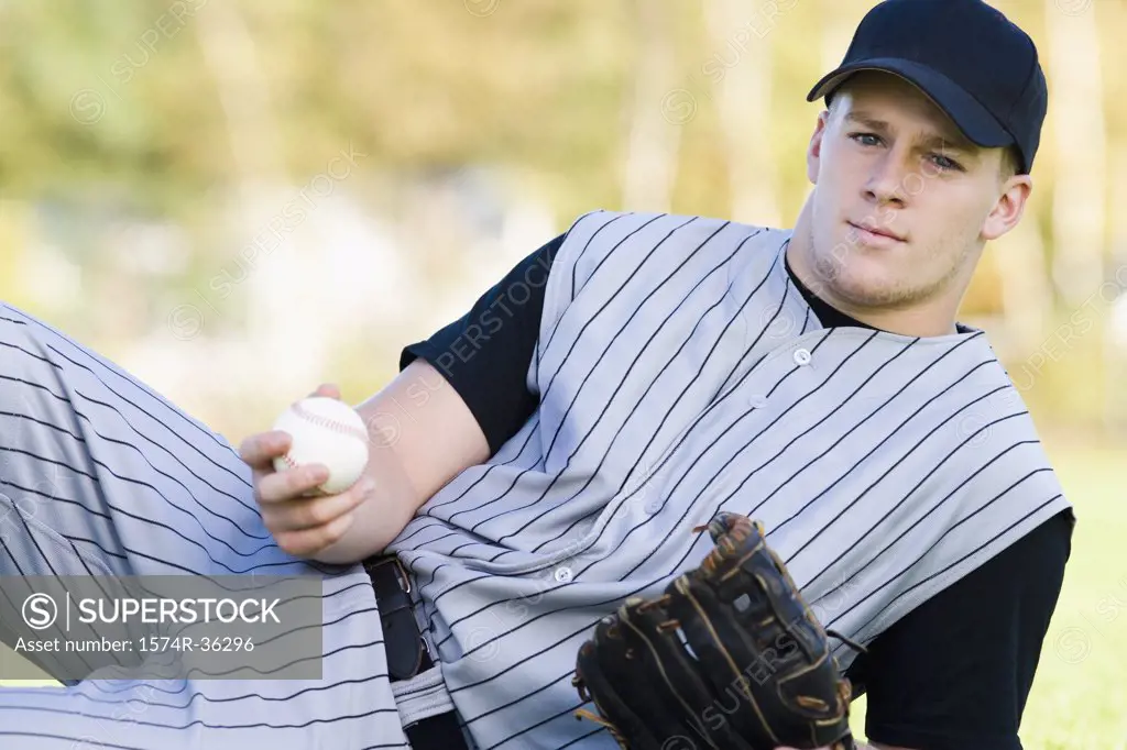 Man reclining and holding a baseball