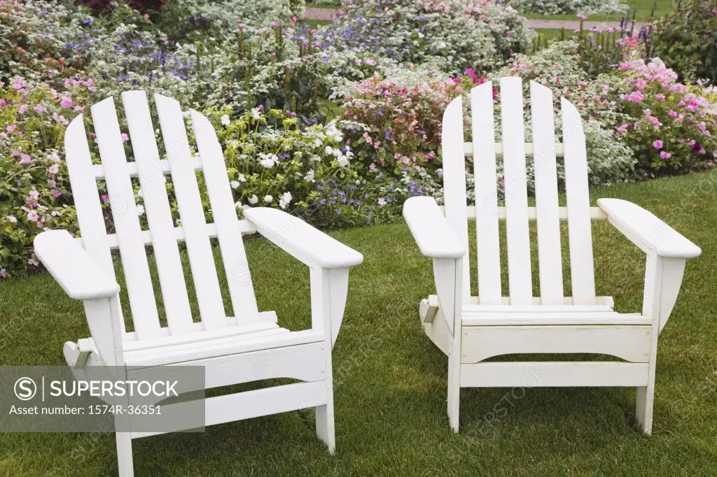 Two adirondack chairs in a garden
