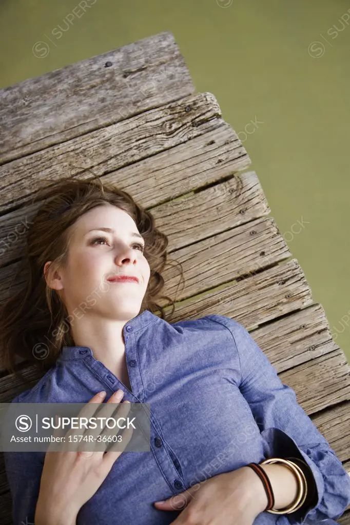 Woman lying on a pier and day dreaming
