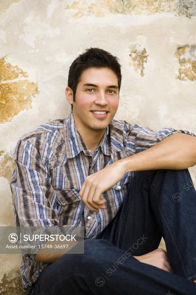 Portrait of a man sitting against a wall and smiling
