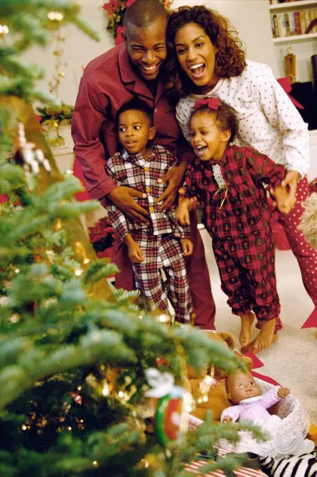 Parents with their son and daughter near a Christmas tree