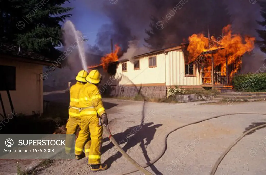 Back view of firefighters fighting house fire