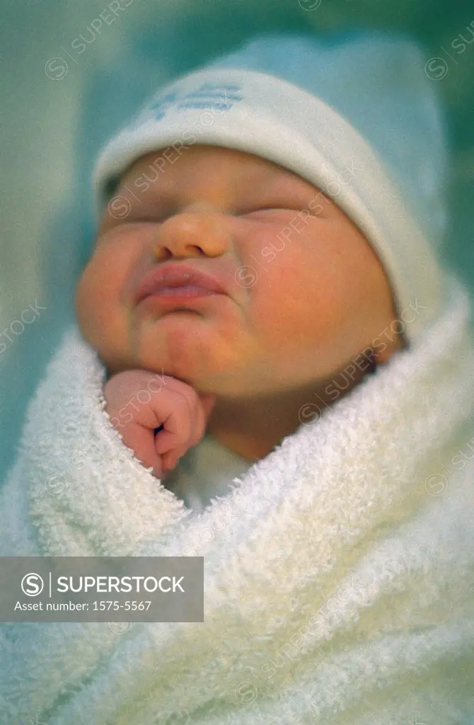 Swaddled pouting newborn baby