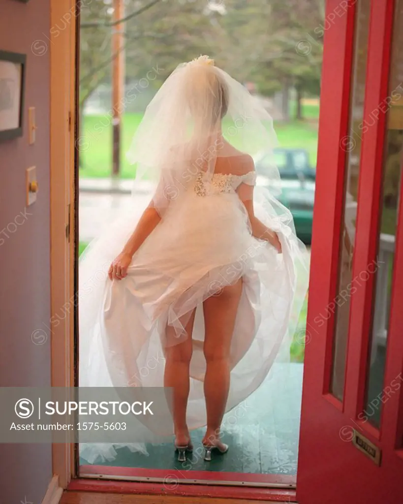 Woman walking out door with wedding dress tucked in her panties