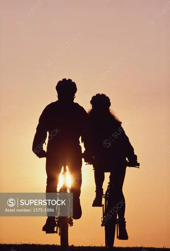 Silhouette of couple biking