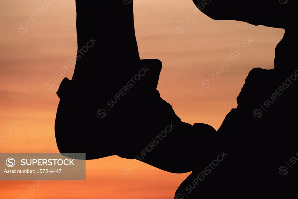 silouette of rock climbers foot at sunset