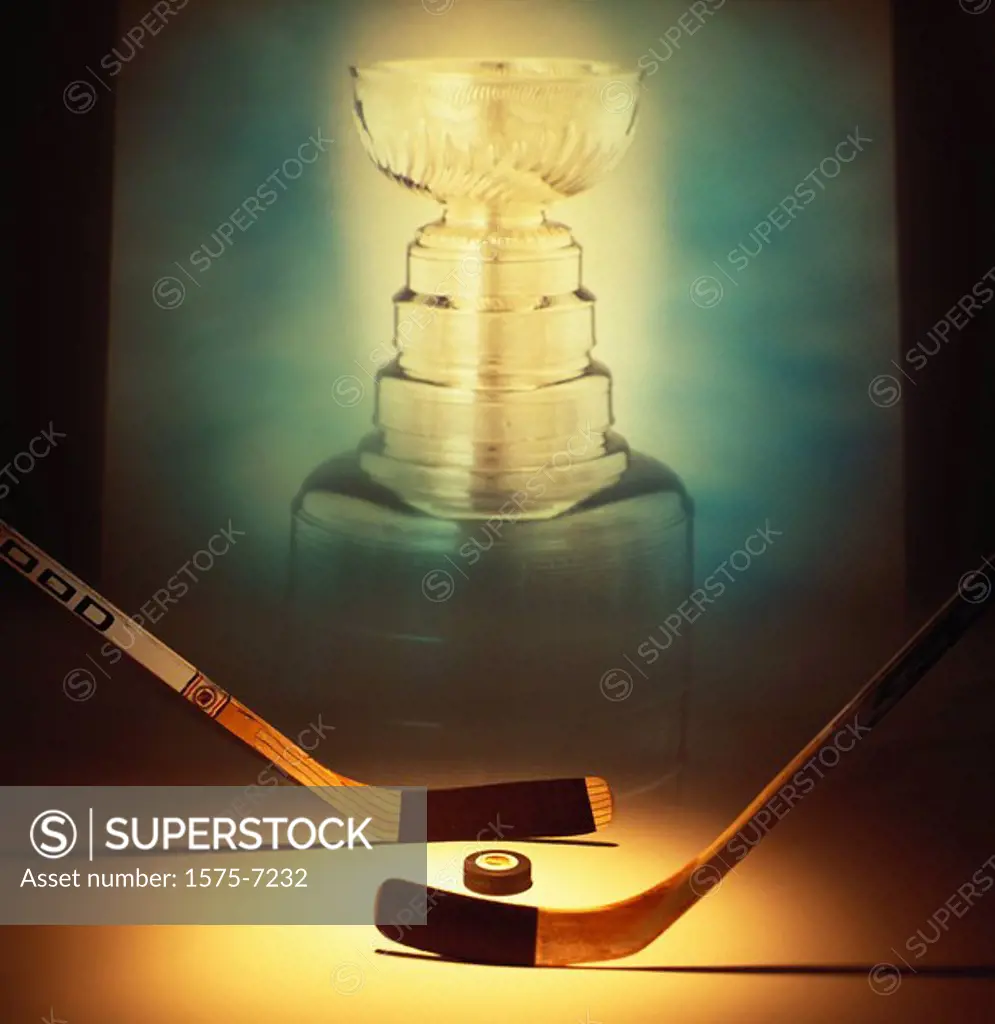 Hockey sticks in face off position with picture of the Stanley Cup in the background