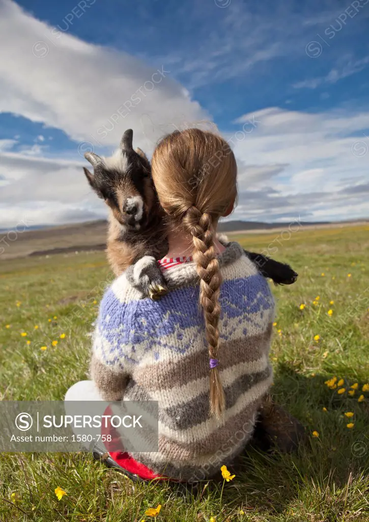 Iceland, Girl holding baby goat