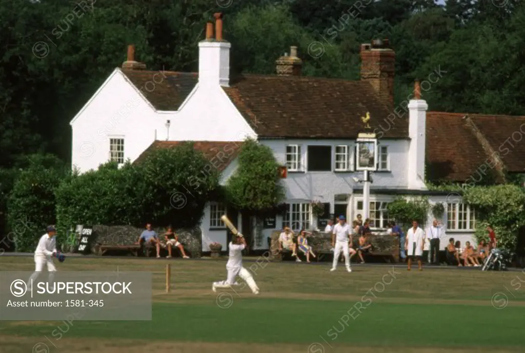 Group of people playing cricket in a field, Tilford, Hampshire, England