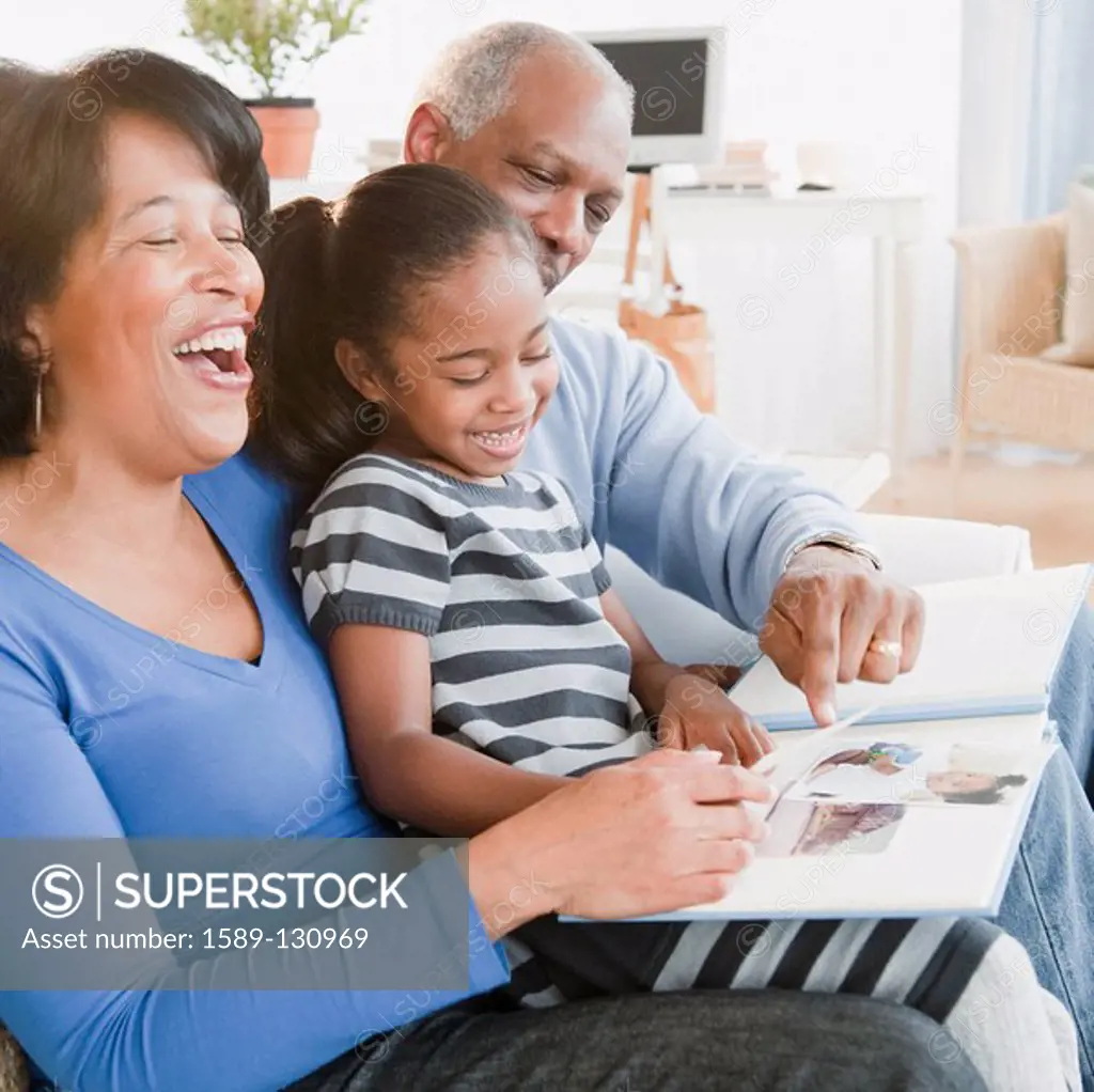 Black grandparents looking at photographs with granddaughter
