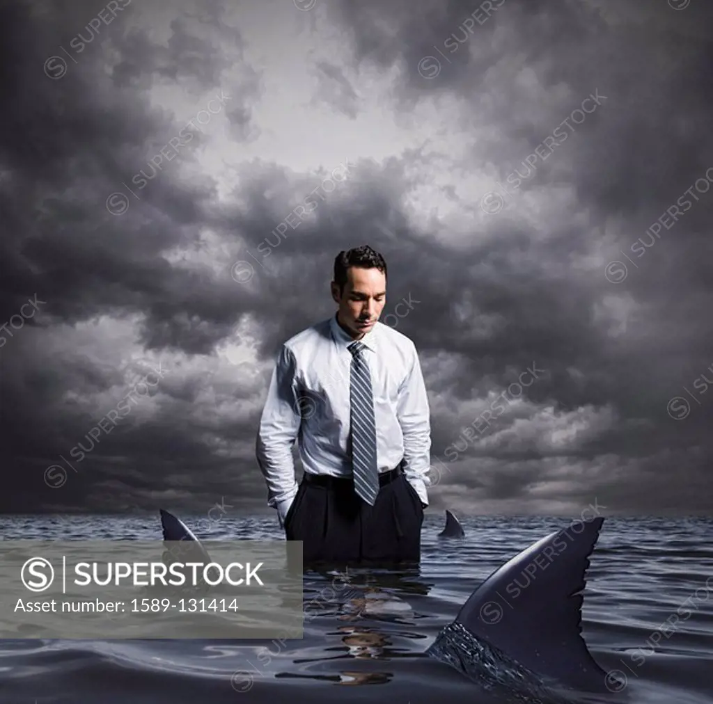 Latin businessman standing in shark infested waters