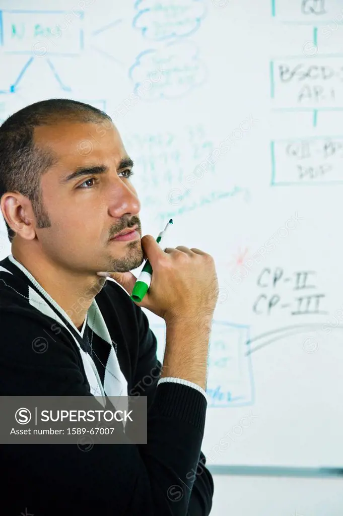 Middle Eastern man thinking near whiteboard