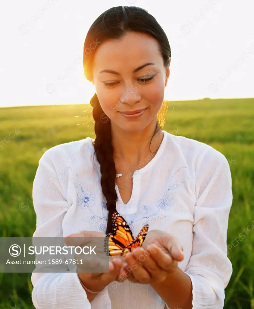 Asian woman holding butterfly in hands