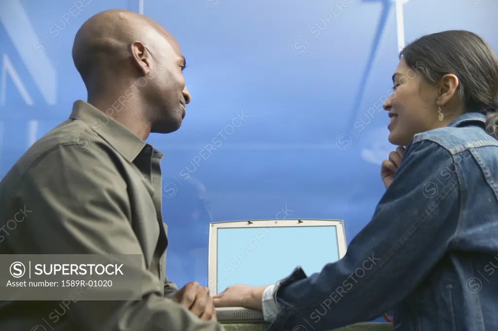 Young couple sitting together in front of a laptop smiling