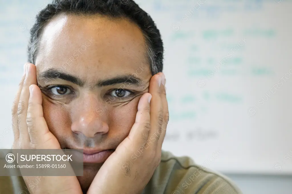 Portrait of a businessman looking at camera with his hands on his face