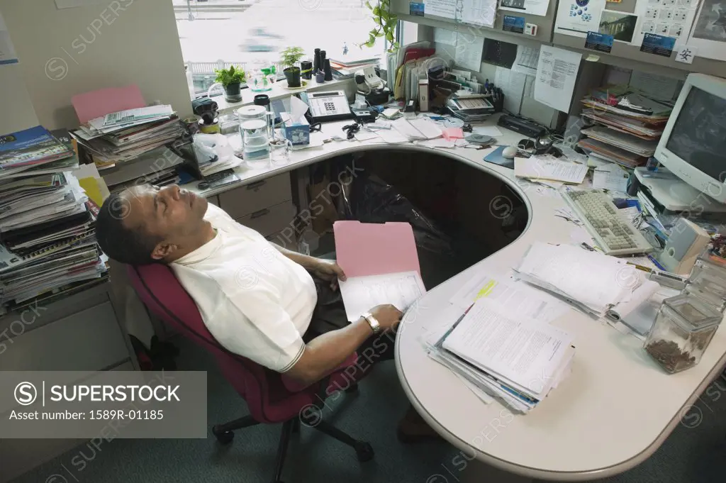 High angle view of a businessman sleeping in a chair at the office
