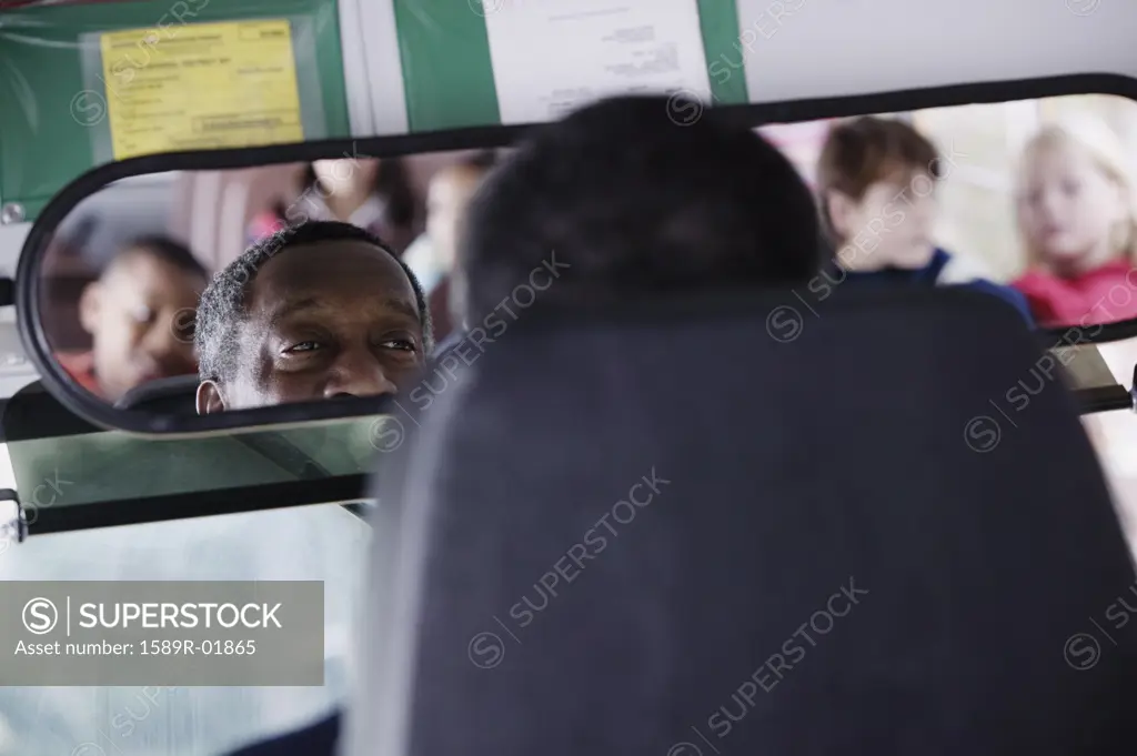 School Bus Driver Looking at Kids in Rearview Mirror