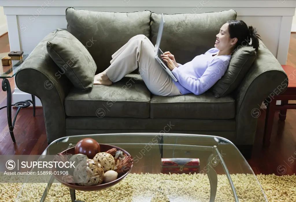 Woman reclined on couch using laptop