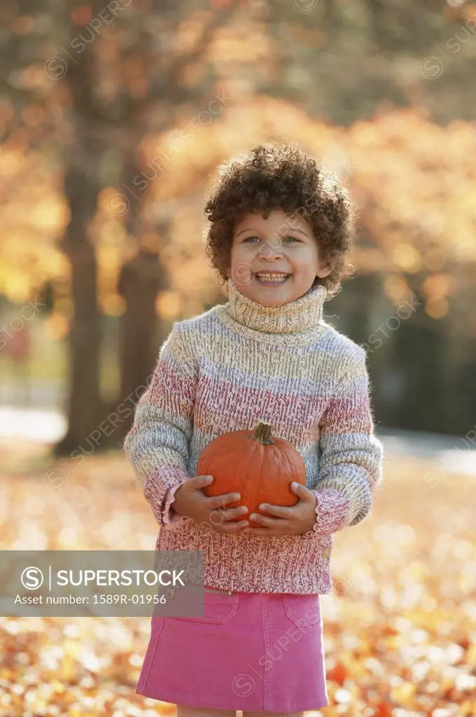 Girl holding a pumpkin smiling