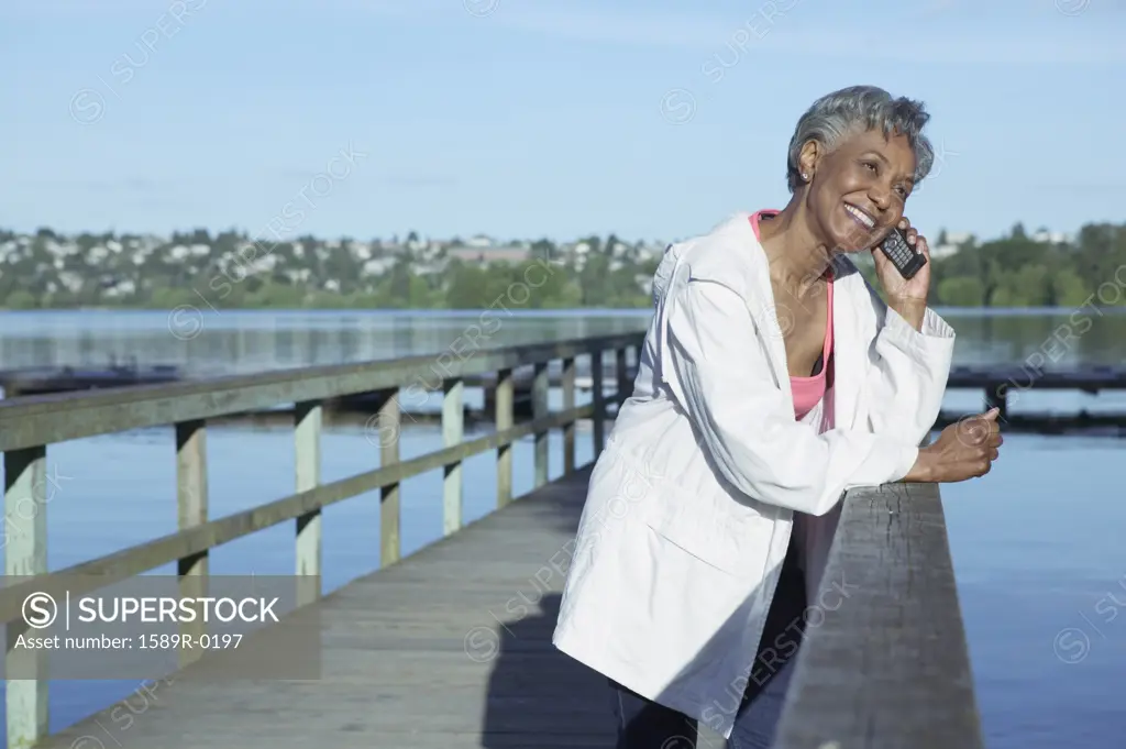 Elderly woman standing on a pier talking on a mobile phone