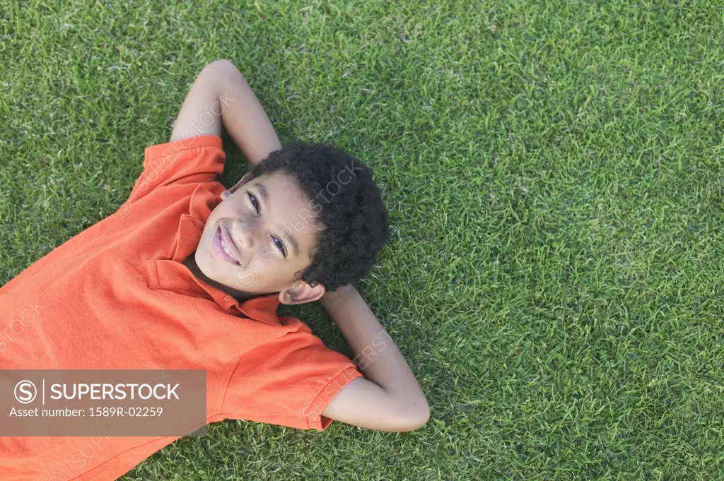 High angle view of a young boy lying on a lawn