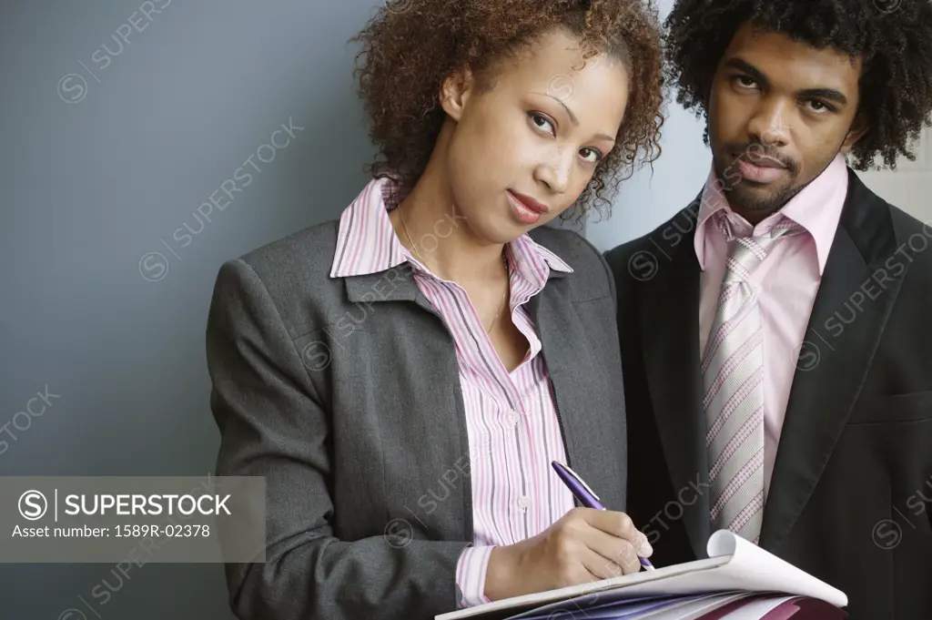 Portrait of a businessman and a businesswoman writing