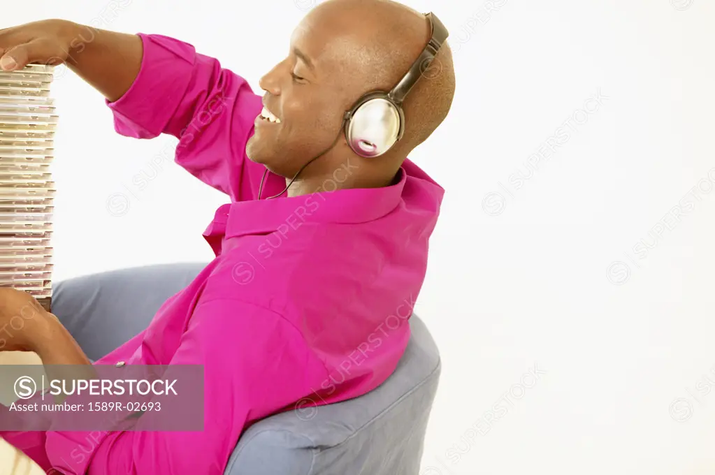Young man sitting on a couch holding a stack of cds