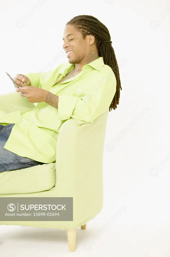 Young man sitting on a couch operating a hand held device