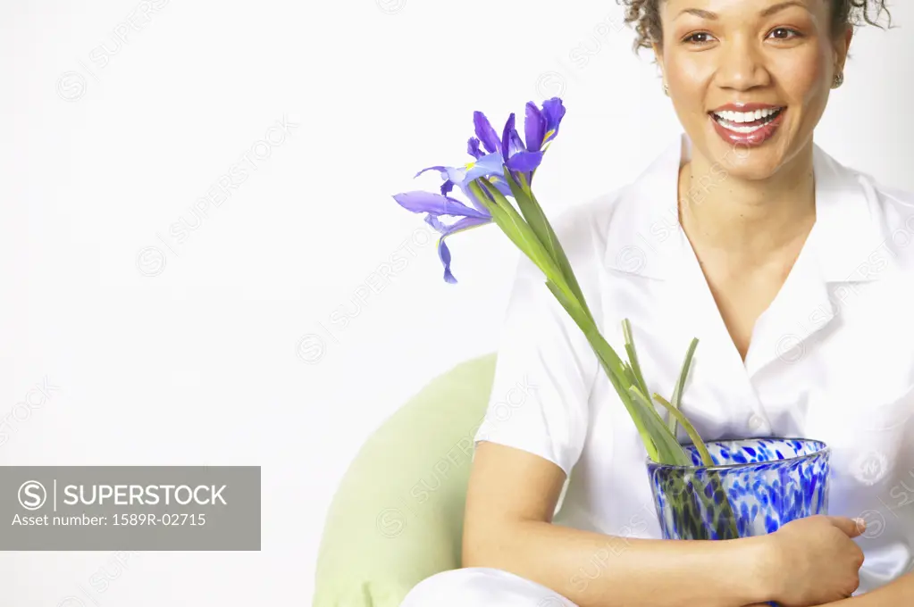 Young woman sitting on a couch holding a flower vase
