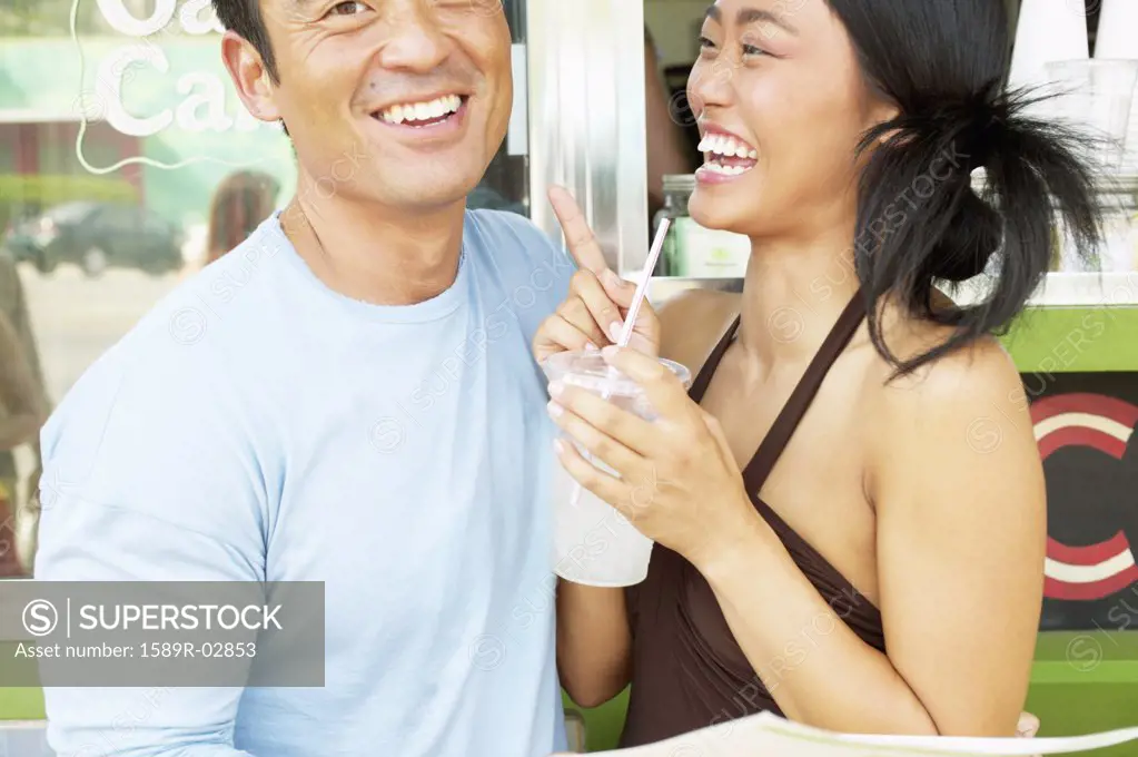Mid adult man and a young woman standing together at a food and drinks stall