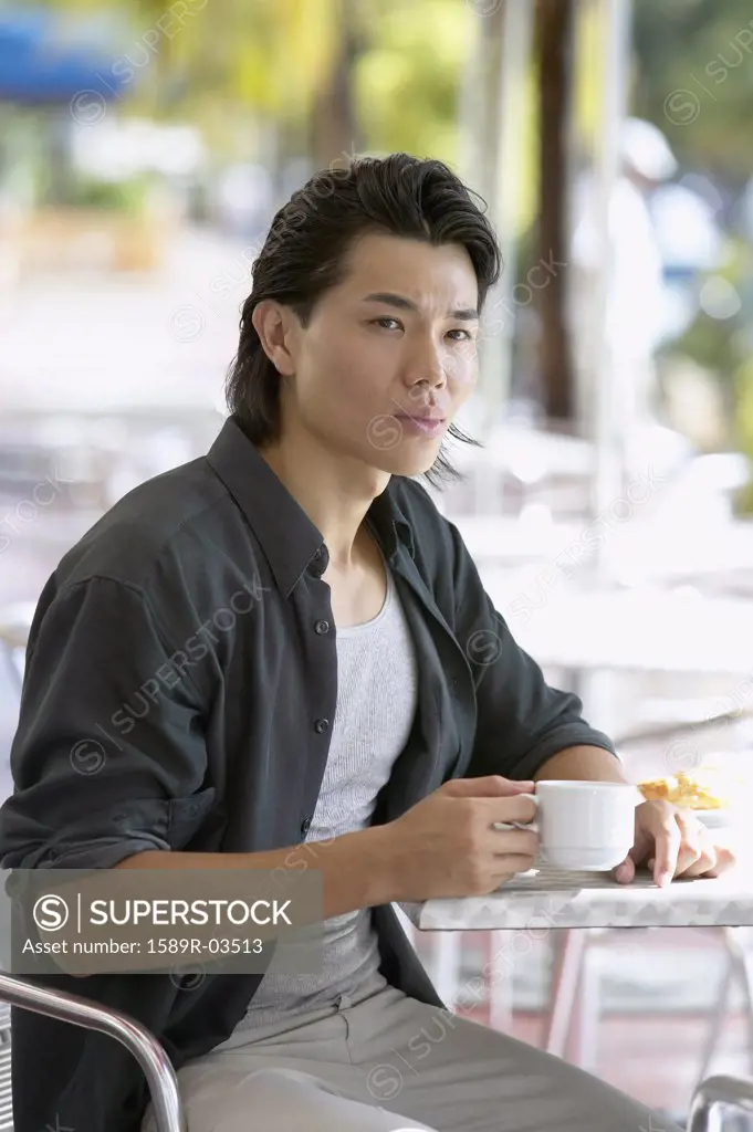 Young man sitting at a table in an outdoor cafe