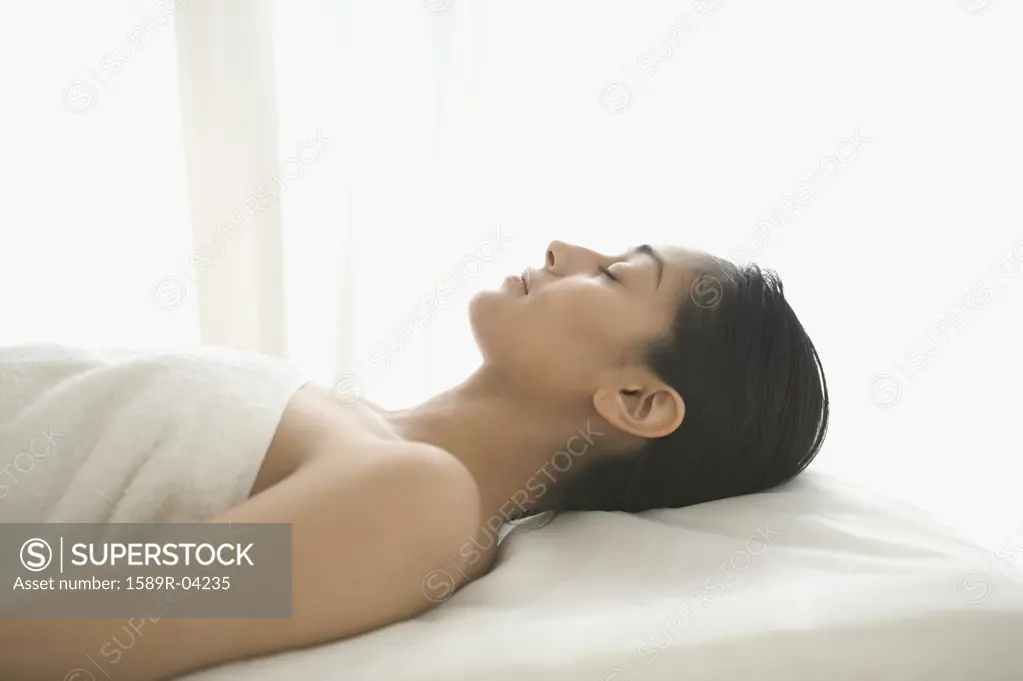 Side profile of a young woman lying on a bed