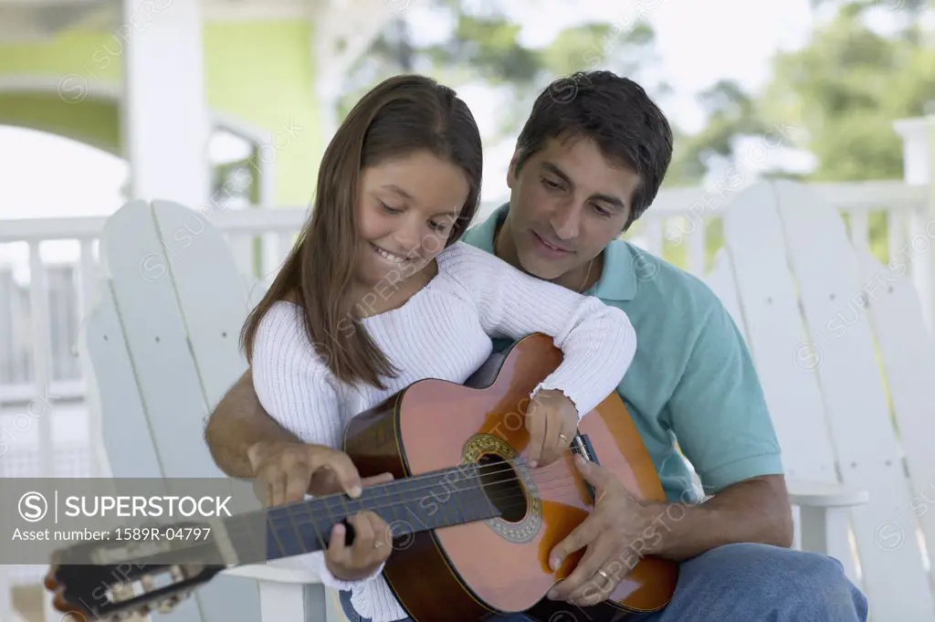 Young man teaching a young girl to play the guitar