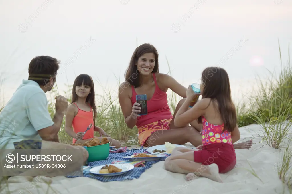 Young couple and their children having a picnic on the beach