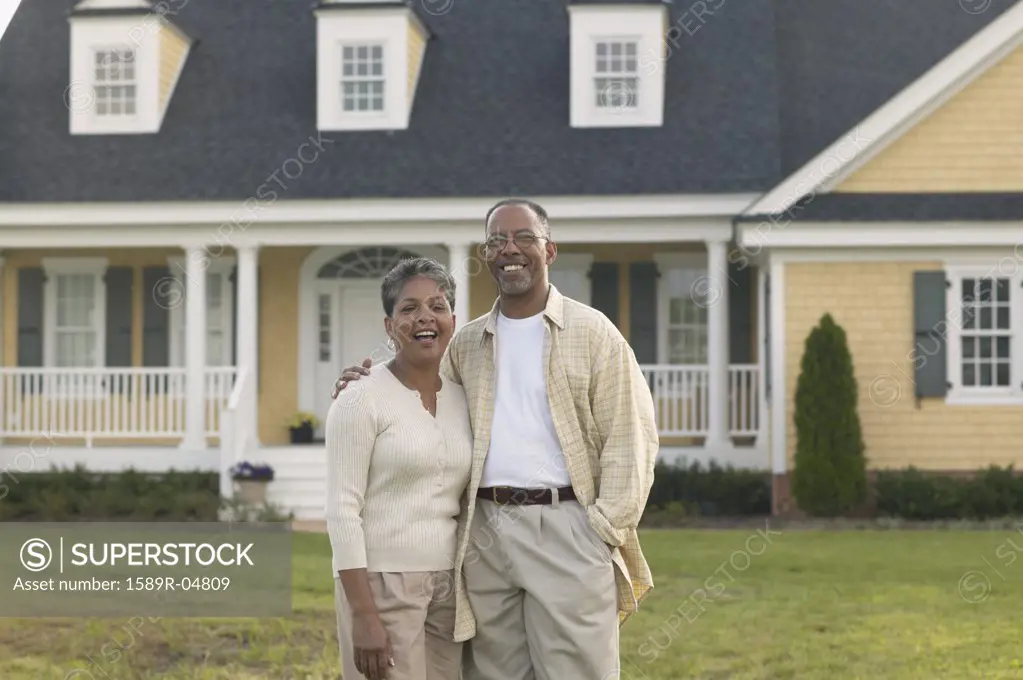 Portrait of a mature couple standing together in front of a house