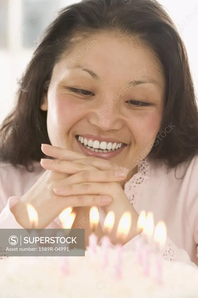 Woman looking at lit candles on a cake smiling