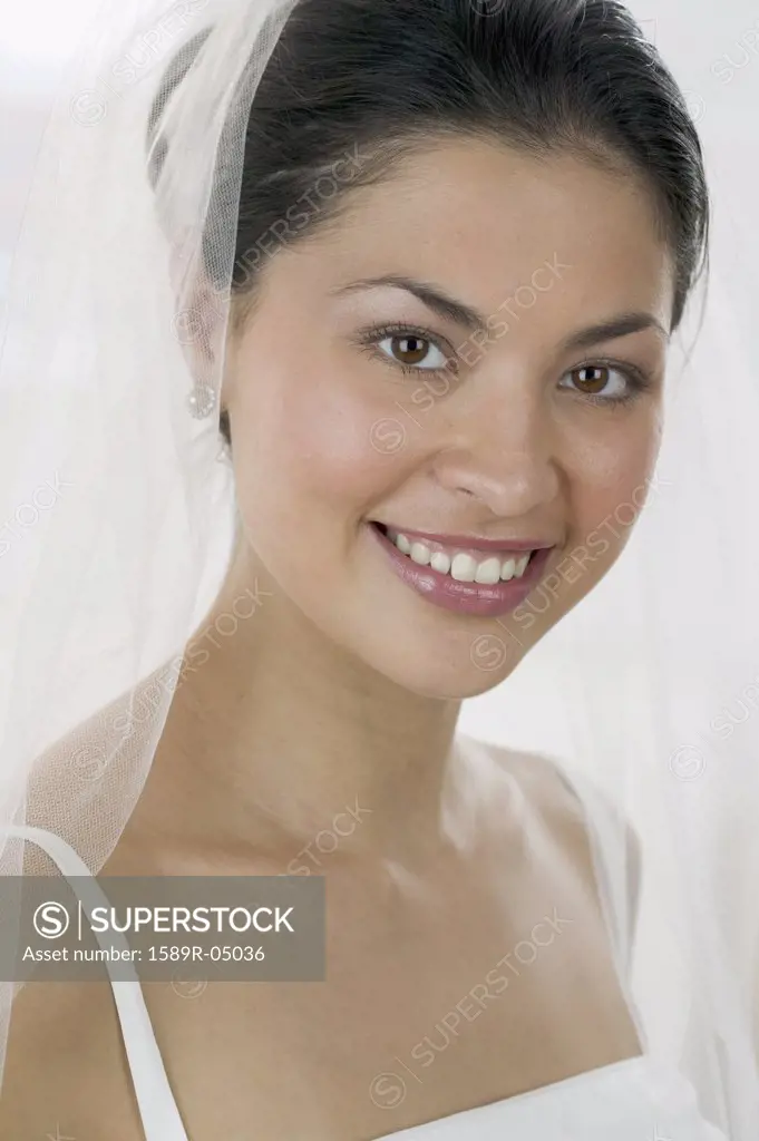 Young woman wearing a wedding gown looking at camera smiling
